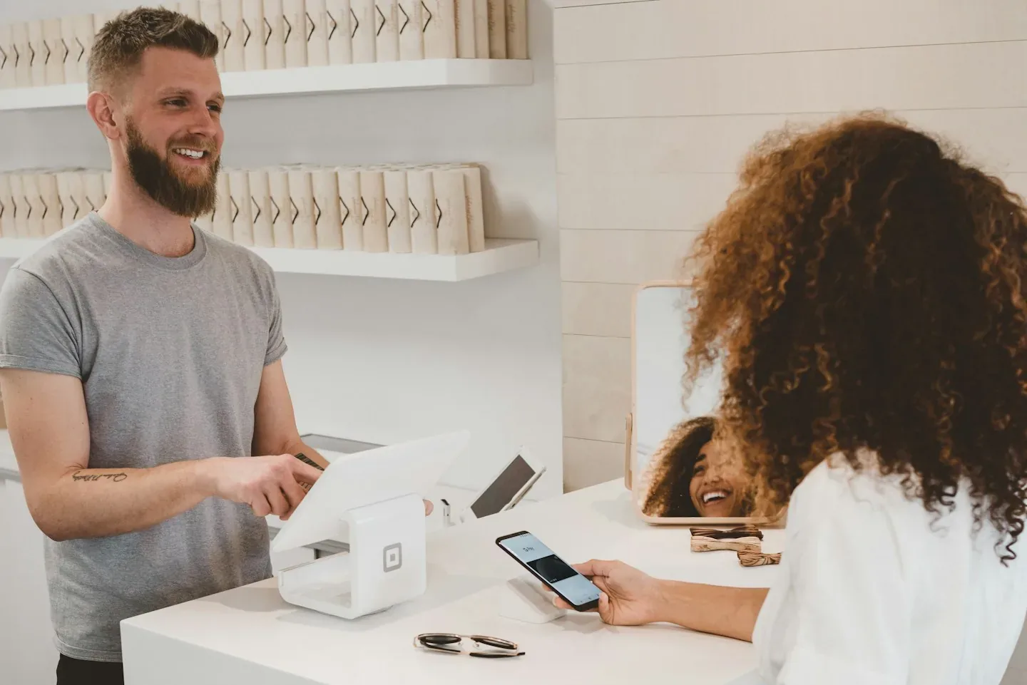 A shop owner helping a customer at the checkout counter