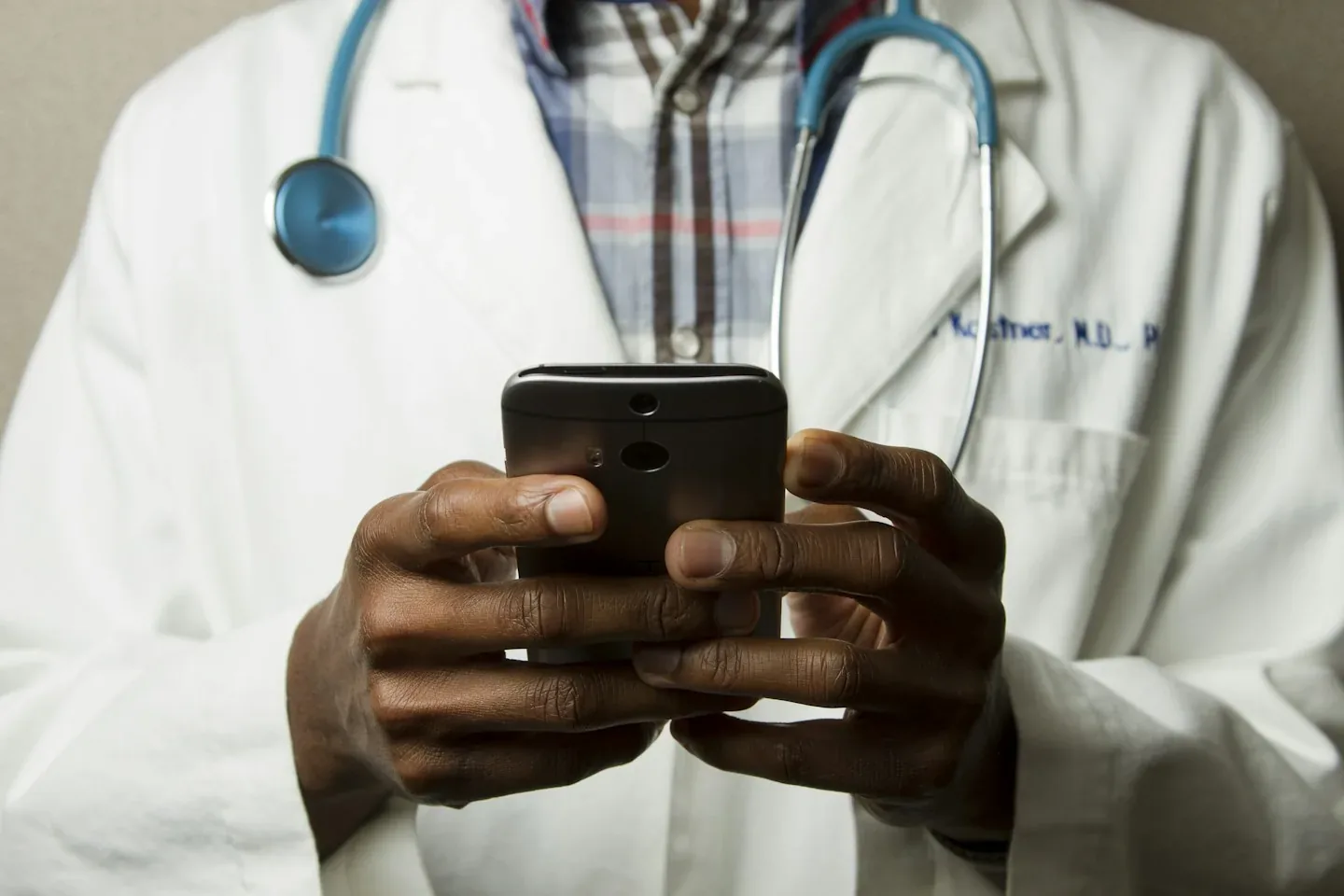 A medical professional wearing a stethoscope and consulting a mobile device