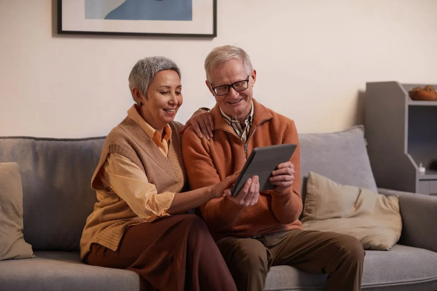 An older couple looking at a tablet together on their sofa